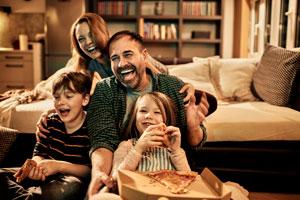 Getty 1144460275 - Close up of a family watching a movie while having pizza