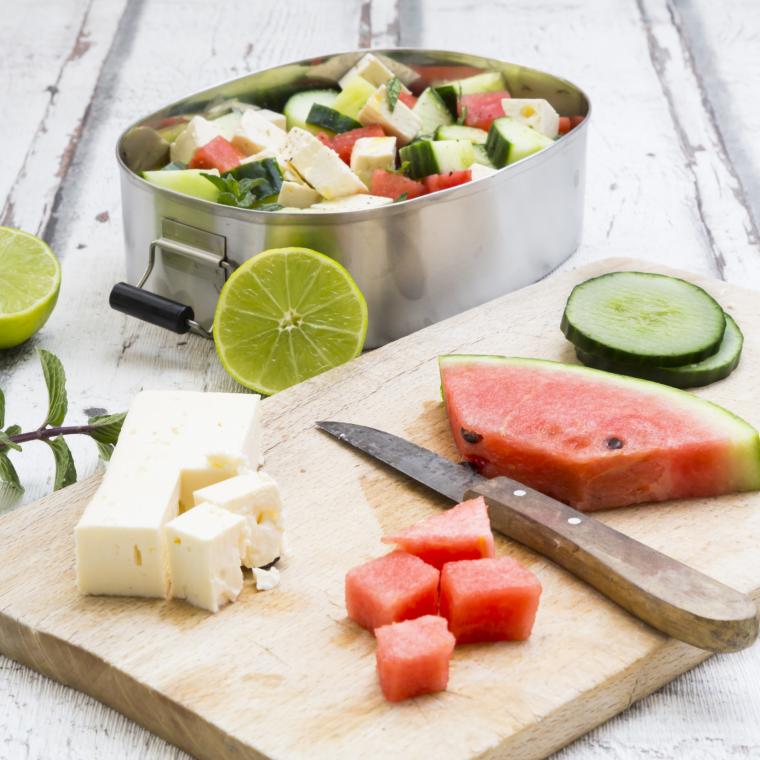 Lunch box, preparation of watermelon salad with feta, cucumber, ment and lime dressing