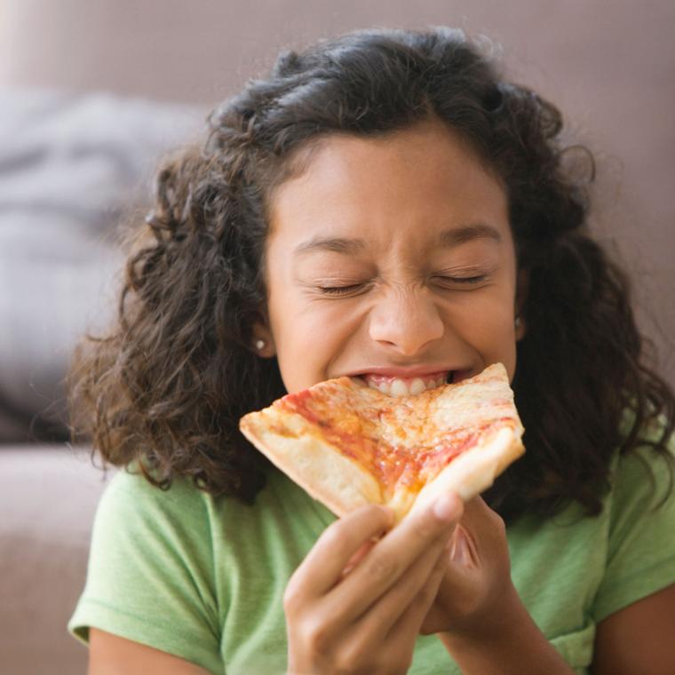 Getty 149616534 - Hispanic girl eating pizza